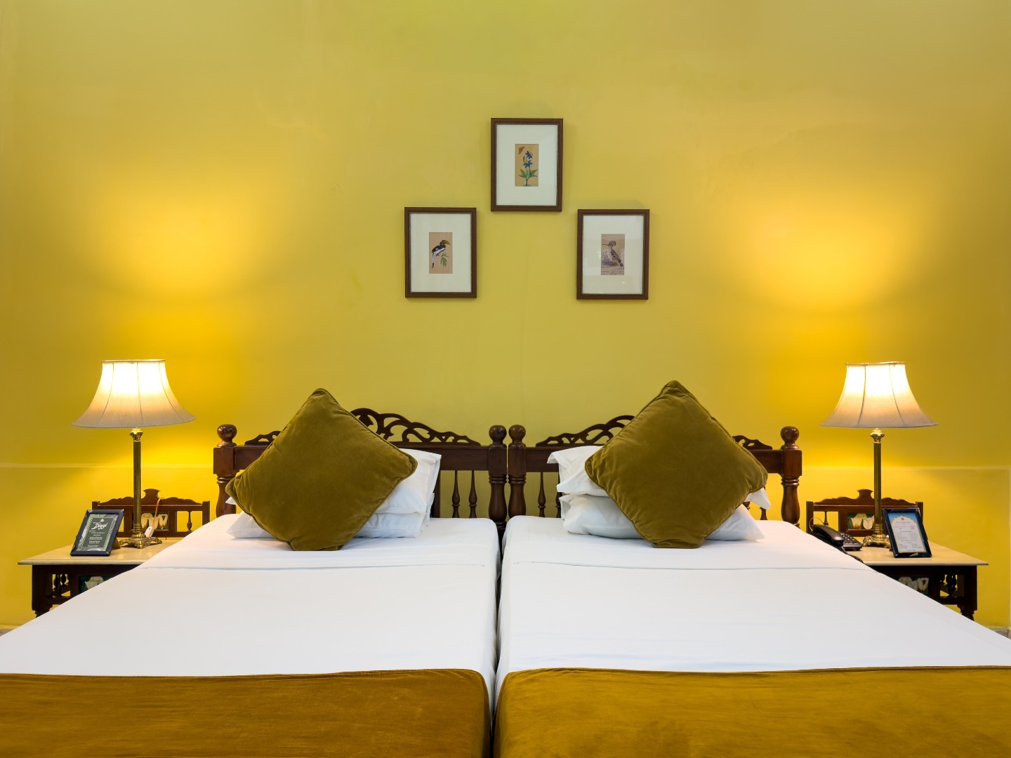 Heritage Standard — twin beds against a yellow wall with framed paintings